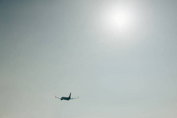 Silhouette of airplane in sky with sun 