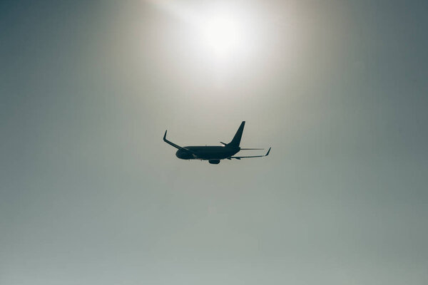 Flight departure of commercial airplane with sun in sky at background