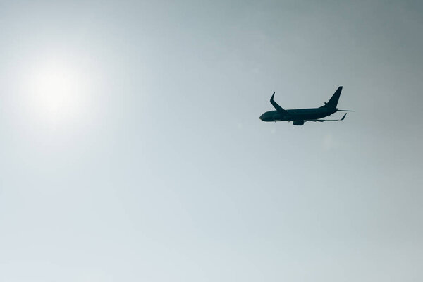 Low angle view of silhouette of jet plane with sun in clear sky
