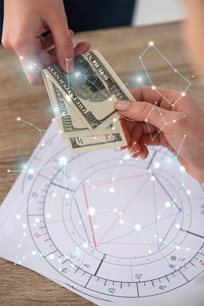 Cropped view of man giving cash to astrologer beside natal charts and constellations