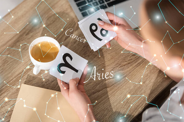 Overhead view of woman holding cards with zodiac signs near constellations  