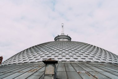 Binanın çatısında arka planda bulutlar olan kulenin düşük açılı görüntüsü