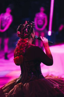 KYIV, UKRAINE - NOVEMBER 1, 2019: Selective focus of artist with microphone and dancers at background in circus clipart