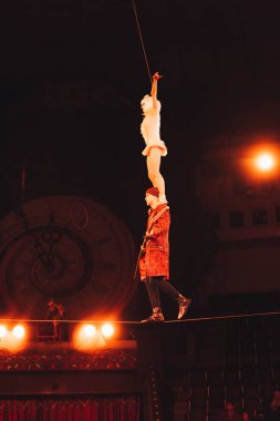 KYIV, UKRAINE - NOVEMBER 1, 2019: Low angle view of air gymnasts balancing on rope in circus  clipart