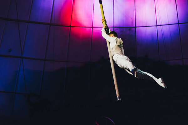 KYIV, UKRAINE - NOVEMBER 1, 2019: Air gymnast performing exercise with pole in circus