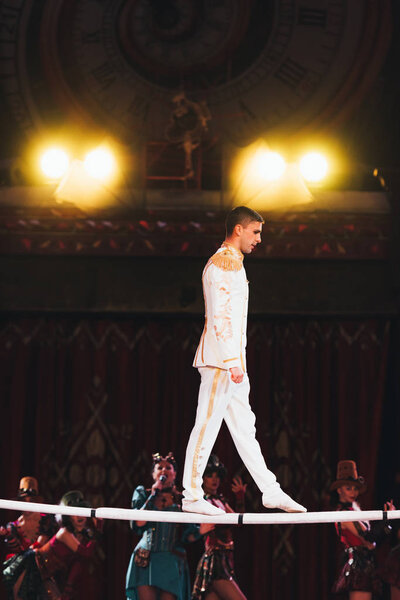 KYIV, UKRAINE - NOVEMBER 1, 2019: Side view of air gymnast balancing on pole with artists in circus