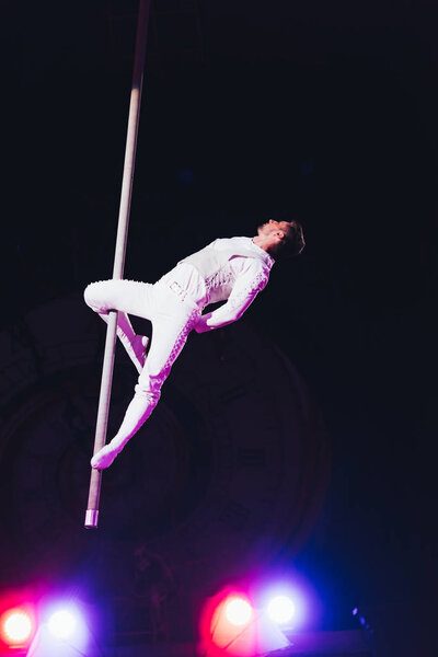 KYIV, UKRAINE - NOVEMBER 1, 2019: Handsome air gymnast with pole performing in circus isolated on black