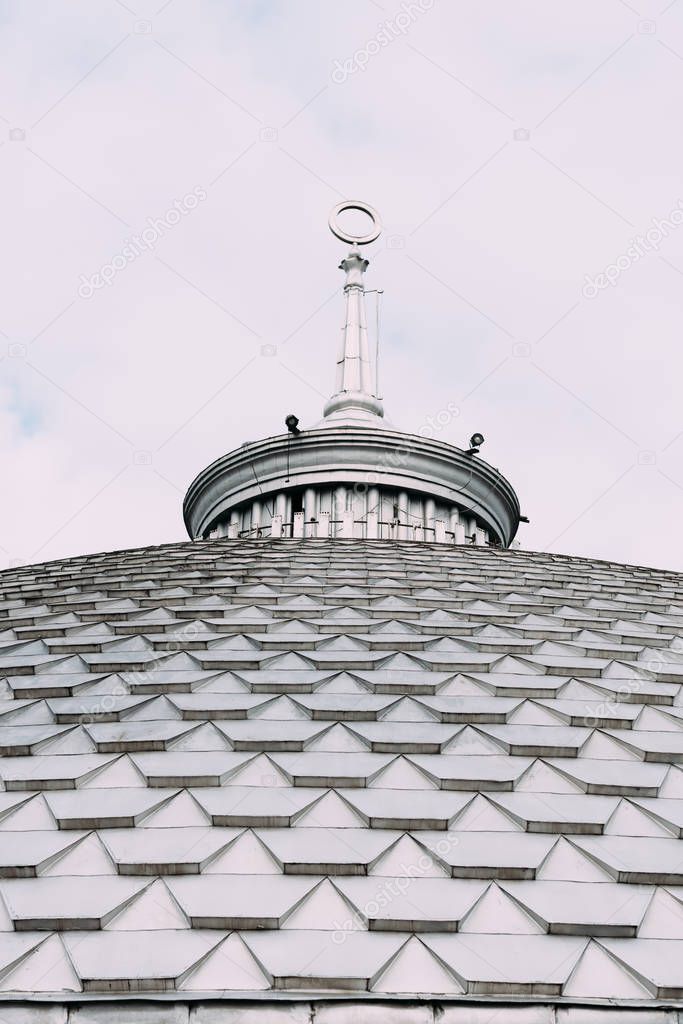 Low angle view of spire on roof of building with cloudy sky at background