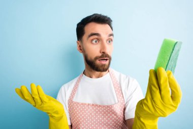 Mavinin üzerindeki süngere bakan noktalı önlüklü şaşırmış adamın seçici odağı. 