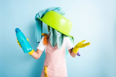 Çamaşır deterjanı tutan adamın üstünde plastik kase ve kirli çamaşırlar. 