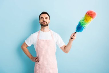 Önlüklü yakışıklı adam elinde toz fırçasıyla mavi 