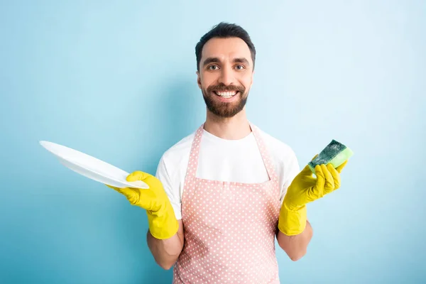 Fröhlicher Mann Gepunkteter Schürze Mit Teller Und Schwamm Auf Blau — Stockfoto