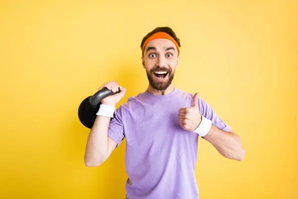 Cheerful Sportsman Holding Heavy Dumbbell Showing Thumb Isolated Yellow — 스톡 사진