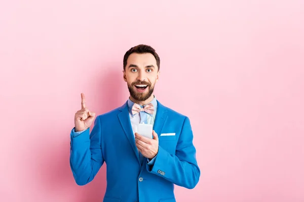 Χαρούμενος Επιχειρηματίας Κρατώντας Smartphone Και Δείχνοντας Δάχτυλο Ροζ — Φωτογραφία Αρχείου