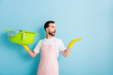 Kirli çamaşırları tutan ve mavi ellerle işaret eden heyecanlı sakallı adam. 
