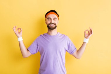 Neşeli adam meditasyon yapıyor ve sarı üzerinde gülümsüyor.