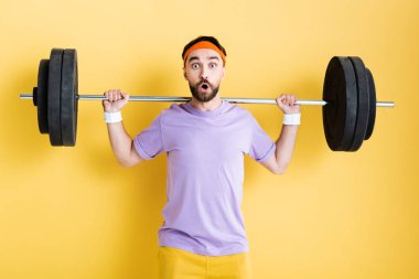 shocked sportsman working out with barbell on yellow clipart
