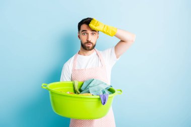 Yakışıklı sakallı adam kirli çamaşırları mavinin üstünde tutuyor. 