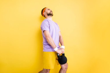 tired sportsman holding heavy dumbbell on yellow clipart