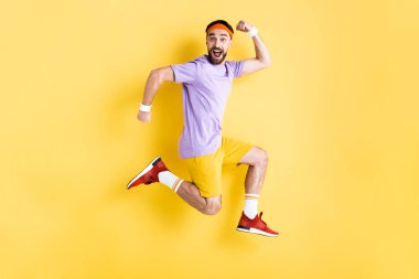 happy man in sportswear jumping on yellow clipart