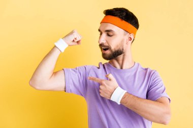 Saç bandı takan sporcu sarıda izole olmuş kasları işaret ediyor.