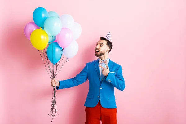 Takım Elbiseli Mutlu Adam Pembe Balonları Işaret Ediyor — Stok fotoğraf