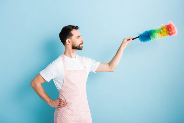 вид сбоку на бородатого человека, держащего пылевую щетку на голубом фоне
 