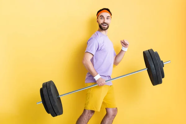 Happy Sportsman Holding Heavy Barbell While Walking Yellow — 스톡 사진