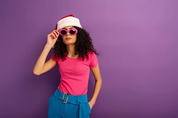 Elegante Chica Raza Mixta Santa Sombrero Tocando Gafas Mientras Sostiene —  Fotos de Stock