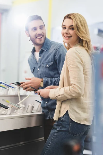 Novio Novia Sonrientes Sosteniendo Nuevos Teléfonos Inteligentes Tienda Electrodomésticos — Foto de Stock