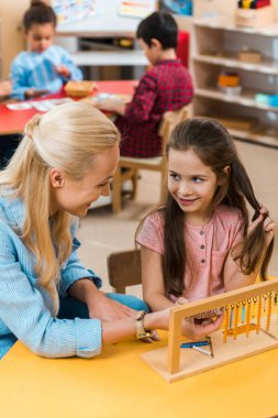 Montessori okulunda çocuklarla oyun oynarken çocuk ve öğretmenin birbirlerine gülümseyişlerinin seçici odağı