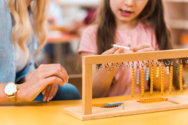 Montessori okulunda öğretmen tarafından oynanan ahşap oyun oynayan çocuğun seçici odak noktası.