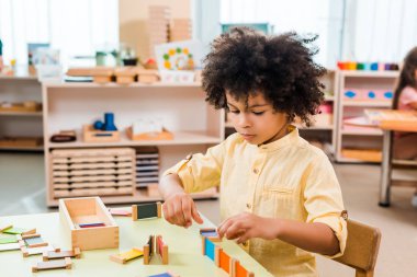 Montessori okulundaki masada eğitim oyunu oynayan Afrikalı Amerikalı çocuğun seçici odak noktası