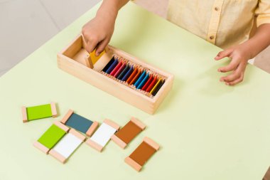 Montessori okulunda renkli tahtalarla eğitim oyunu oynayan çocuk manzarası.