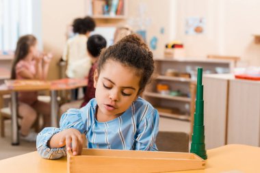 Montessori okulundaki masada ahşap oyun oynayan Afrikalı Amerikalı çocuğun seçici odak noktası