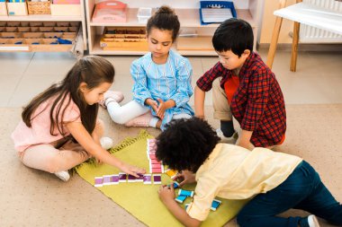 Montessori okulunda ders sırasında yerde renkli oyunlar oynayan çocukların yüksek açılı görüntüsü