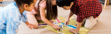 Montessori okulunda çocukların yerde renkli oyunlar oynadığı panoramik bir çekim.