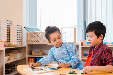Montessori sınıfında masada masa oyunu oynayan çocuklar