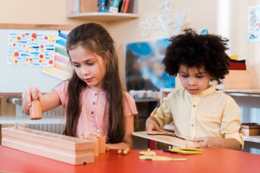 Montessori okulunda ders sırasında ahşap oyunlar oynayan çocukların seçici odağı