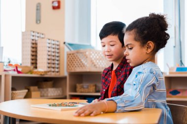Montessori okulunda eğitici oyun katlayan çocukların yan görünümü