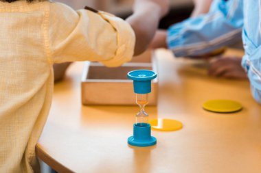 Montessori okulunda eğitim oyunu ve kum saati olan çocukların seçmeli odak noktası.