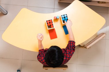 Montessori okulundaki ders sırasında çocukların masalarda renkli oyunlar oynamalarına genel bir bakış. 