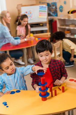 Montessori okulunda çocuklar ve öğretmenle oynayan çocukların seçici odak noktası