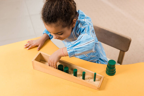 Overhead view of african american kid playing wooden game at table in montessori school