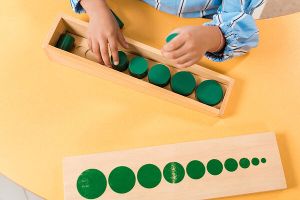 Cropped view of kid with wooden board game at table in montessori school 