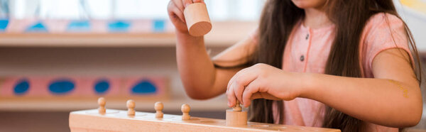 Panoramic shot of child playing with wooden game at table in montessori school, cropped view