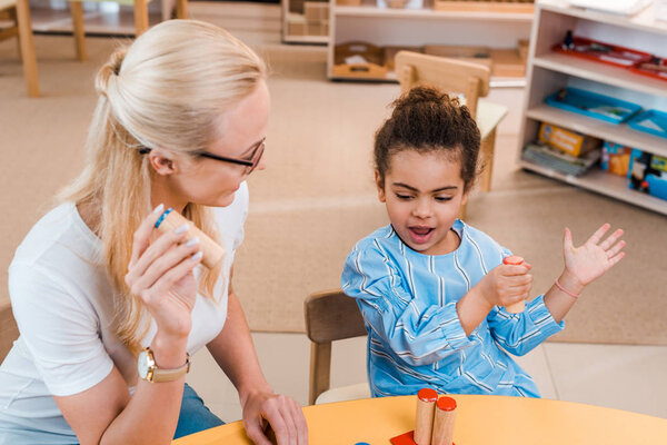 Teacher playing educational game with child at desk in montessori school