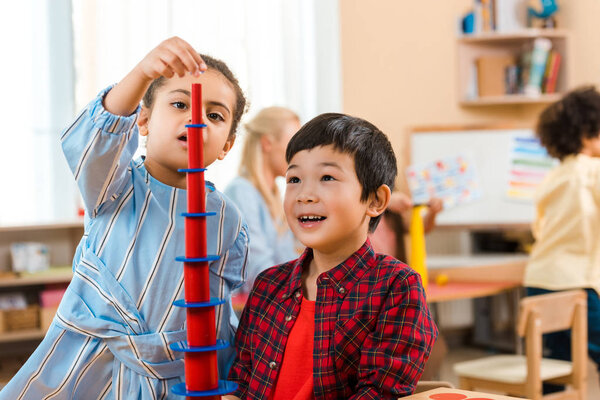 Selective focus of kids playing educational game with teacher and child at background in montessori class