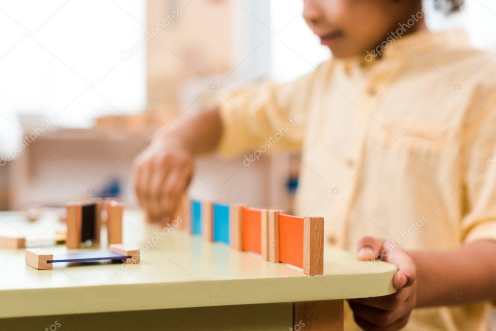 Selective focus of kid playing educational game in montessori school, cropped view