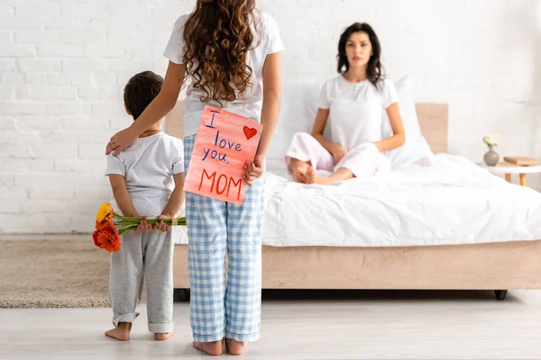 Vista Posterior Hermano Hermana Sosteniendo Flores Amo Tarjeta Mamá Mujer —  Fotos de Stock